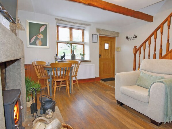 Un salon chaleureux avec une cheminée, des meubles en bois, un coin repas et un escalier.