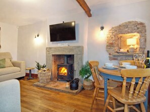 A cozy living room with a fireplace, a television mounted above it, and a stone wall.