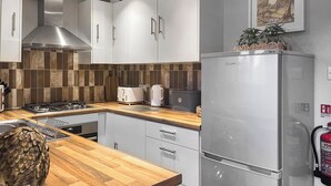 Une cuisine moderne avec des armoires blanches, une hotte en acier inoxydable, un plan de travail en bois et un réfrigérateur en acier inoxydable.