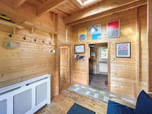 Een houten interieur met een kitchenette, een deur naar een andere kamer en kunstwerken aan de wanden.