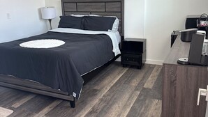 A modern hotel room with a large bed, a bedside table, a desk, and a chair. - Charming studio in delightful Salem with central heating and cooling. (Salem)