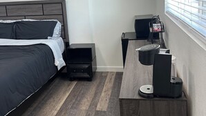 A bedroom with a bed, nightstand, desk, and window with blinds. - Charming studio in delightful Salem with central heating and cooling. (Salem)