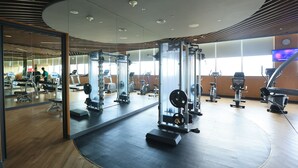 A modern gym with various exercise equipment, large windows, and a wooden floor. - OCEAN BREEZE VILLA CAM RANH (Cam Lam)