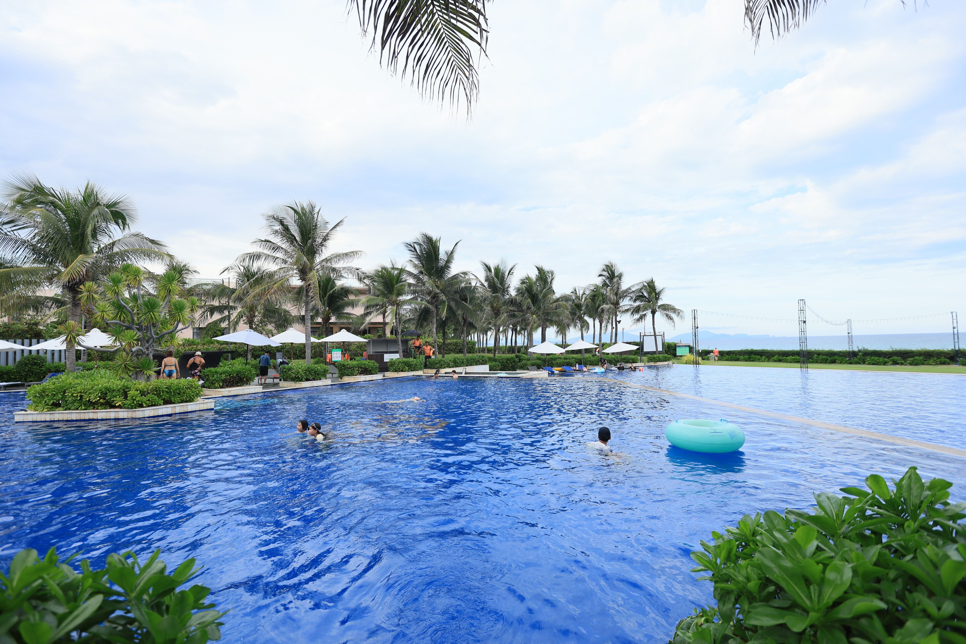 Een buitenzwembad, parasols bij het zwembad en ligstoelen