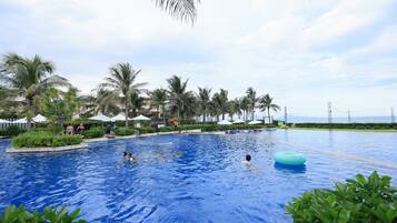 Een buitenzwembad, parasols bij het zwembad en ligstoelen
