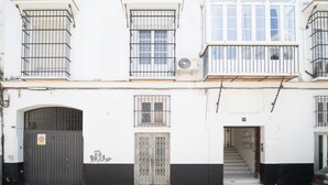 Ein zweistöckiges Gebäude mit einem ehrfurchtgebietenden Eingang, einer Treppe, die zum zweiten Stock führt, und einem Balkon mit Metallgeländern.
