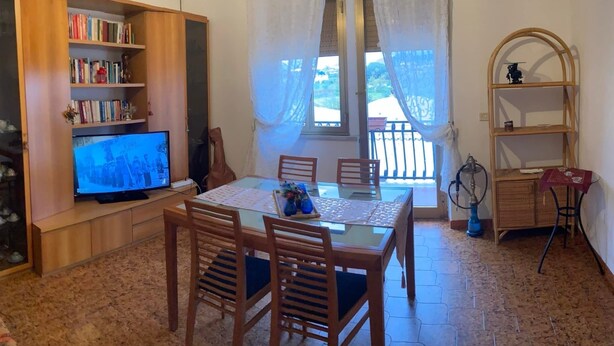 A cozy living room with a television, wooden bookshelf, dining table with chairs, and a balcony with a hookah. - My home Ideal for relaxation and tranquility (Albano Laziale)
