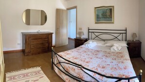 A bedroom with a bed, a wooden dresser, a nightstand, a lamp, a painting, and a door. - My home Ideal for relaxation and tranquility (Albano Laziale)