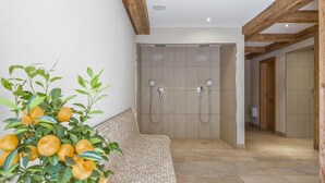A modern bathroom with a shower, tiled walls, and a wooden bench. - Holiday Apartment with a spa next to the gondola (Brixen im Thale)