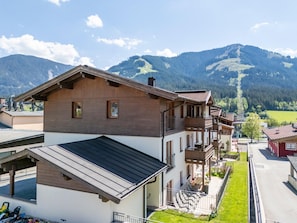 A multi-story building with balconies, a covered outdoor area, and a view of mountains.
