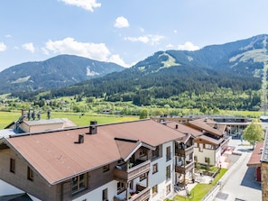 Un quartier résidentiel avec des immeubles à plusieurs étages, un espace vert et des montagnes en arrière-plan.