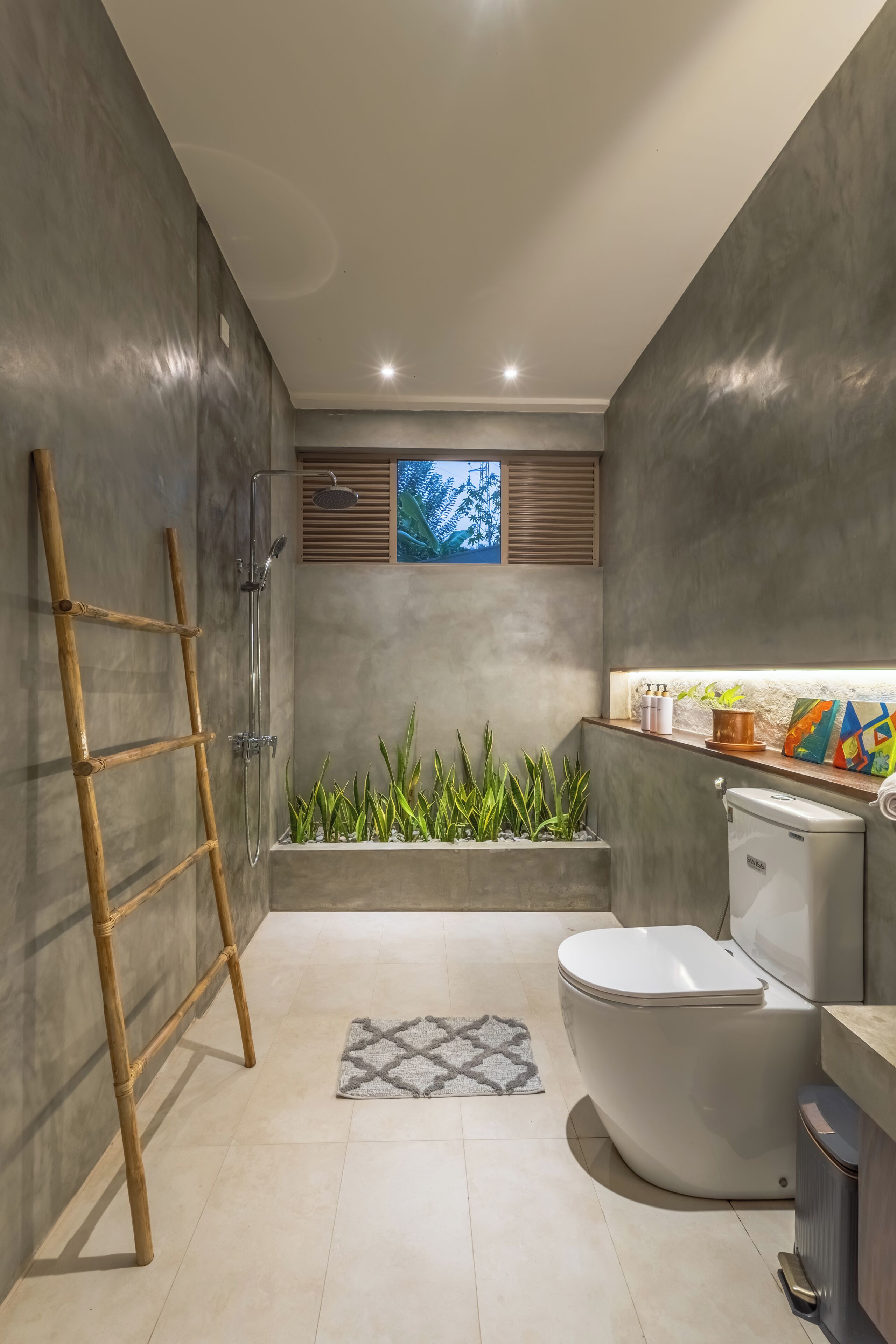 A modern bathroom with a shower, toilet, and a small planter with plants.