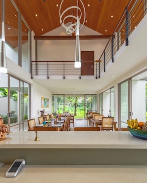 A spacious dining area with high ceilings, large windows, and a modern chandelier.