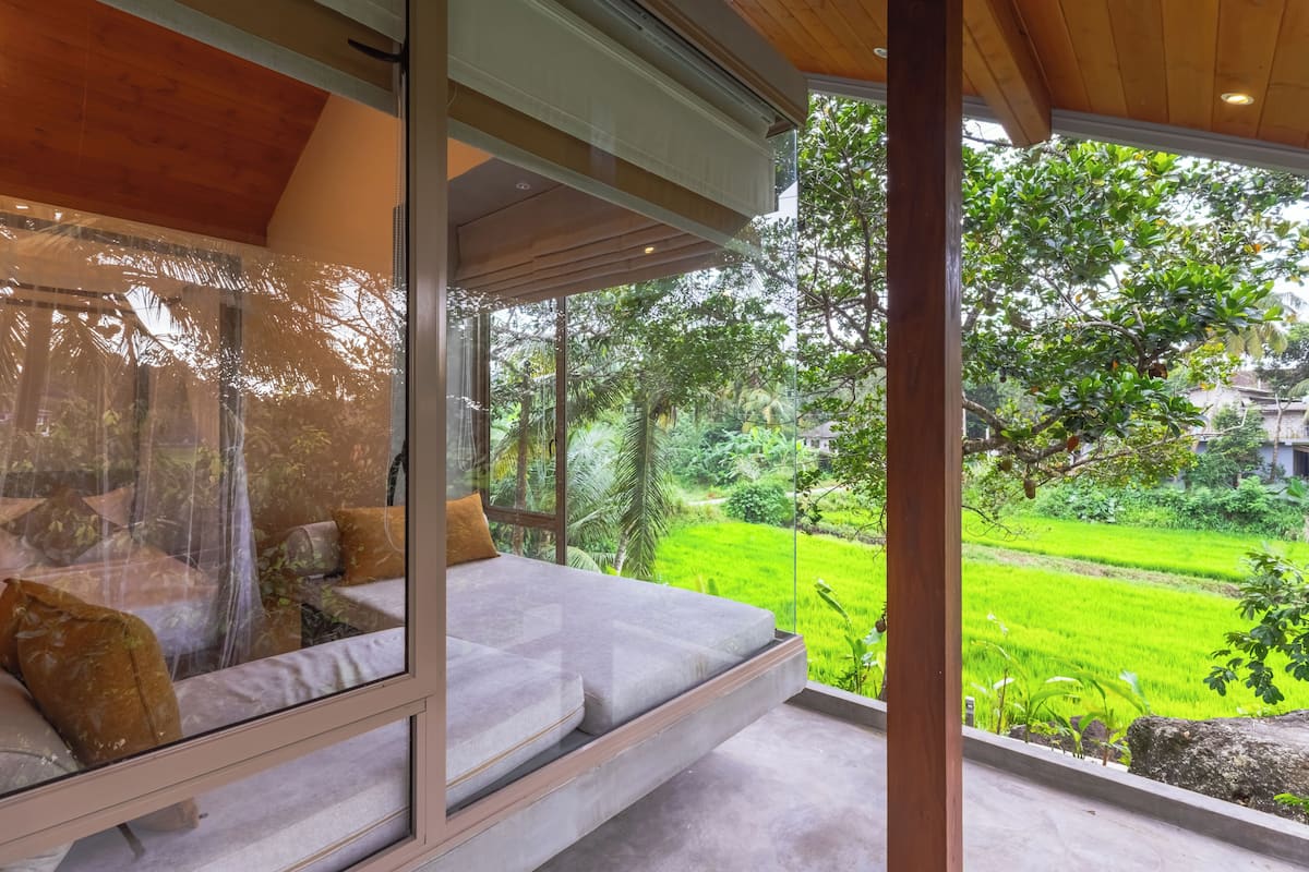 Quarto com uma grande janela com vista para uma paisagem verdejante.