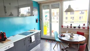 Una cocina moderna con un amplio ventanal, un comedor con mesa redonda y vistas a edificios.