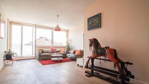 Un salón espacioso con un ventanal grande, un conjunto de sofás, una mesa de centro y una escultura de un caballo.