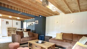 Ein modernes Wohnzimmer mit Holzbalken, einer Sofagarnitur, einem Couchtisch und einem Kuhfellteppich.