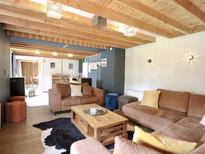 A cozy living room with wooden beams, a sofa, a coffee table, and a rug.