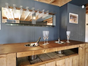 Un espace bar avec un comptoir en bois, un miroir qui reflète le bar et une bouteille de champagne.