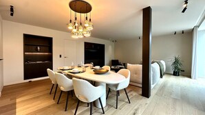 Uma sala de jantar moderna com uma mesa redonda, cadeiras brancas e um candeeiro único.