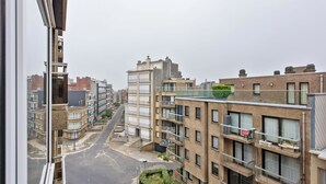 A view of a residential street with multi-story buildings, balconies, and a clear sky. - Cosy flat with central location (Koksijde)