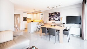A modern apartment with a living room, dining area, kitchen, and a TV.