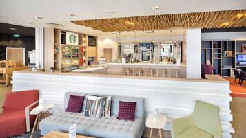 A hotel lobby with a reception desk, seating area, and a bar.