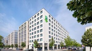 A multi-story hotel with a modern design, featuring a prominent green logo on the side. - Holiday Inn Berlin - City East Side (Berlin)