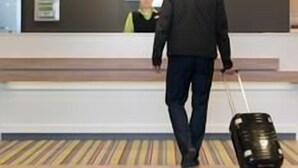 A man walking towards a reception desk in a hotel lobby with a suitcase. - Holiday Inn Berlin - City East Side (Berlin)