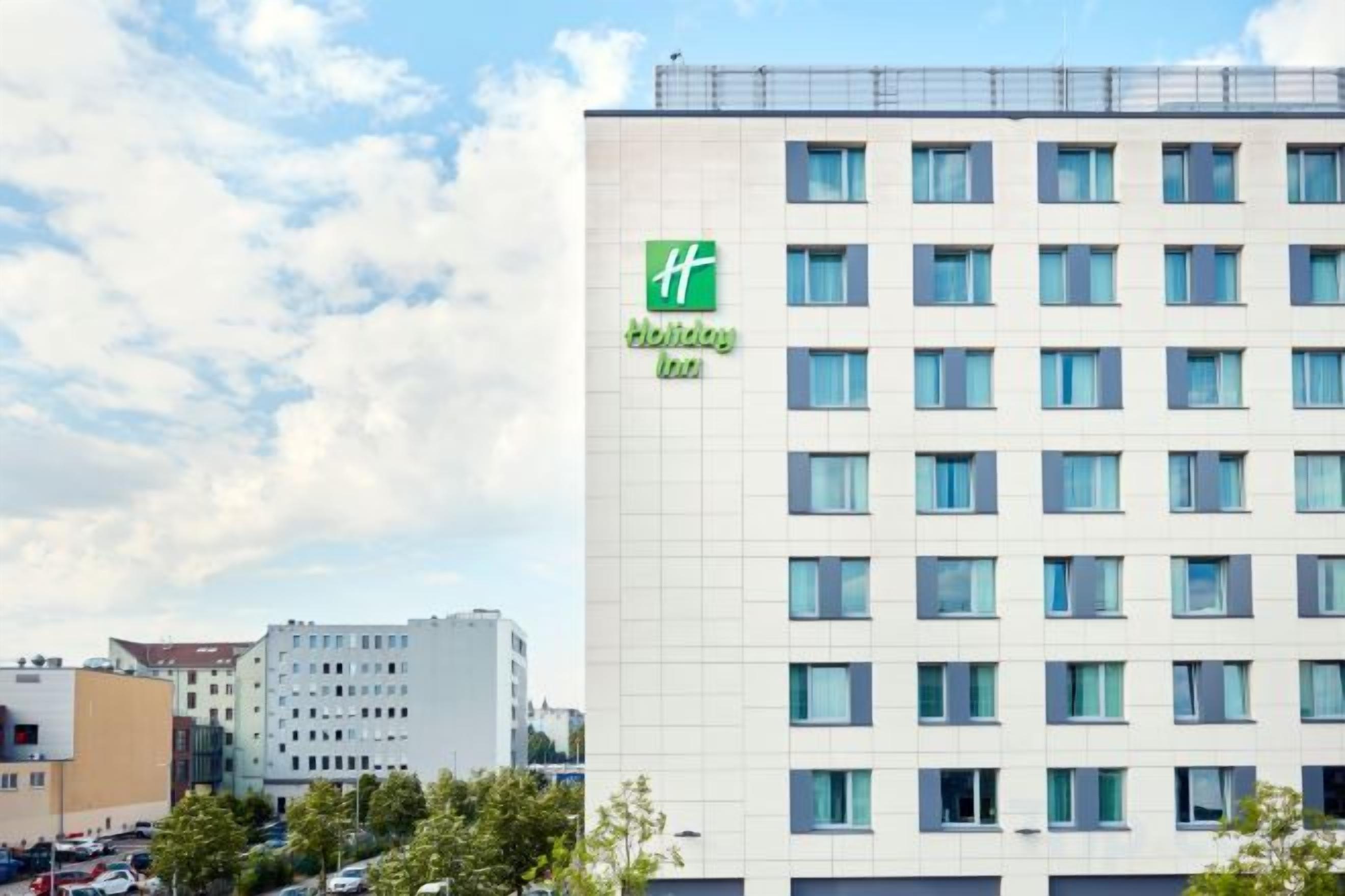 A multi-story building with a 'Holiday Inn' sign, featuring a grid of windows and a flat facade.