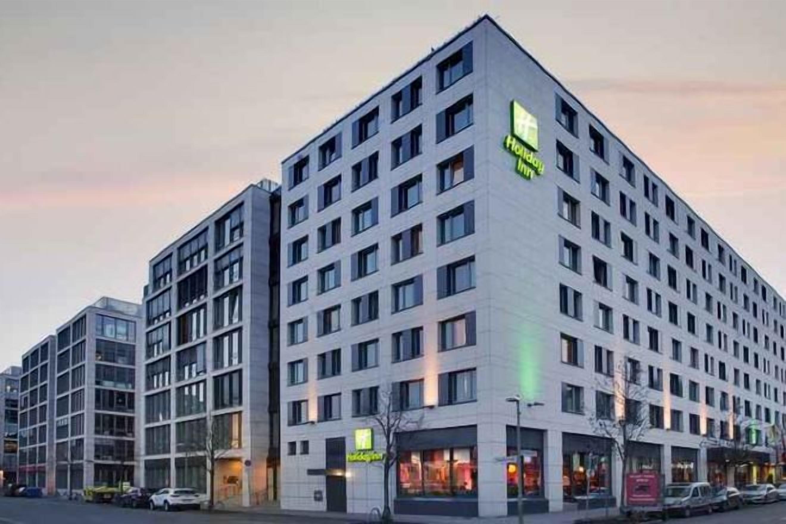 A multi-story hotel with a modern design, featuring a prominent corner entrance and multiple windows.