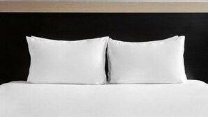 A bed with white bedding and two pillows. - Holiday Inn Berlin - City East Side (Berlin)