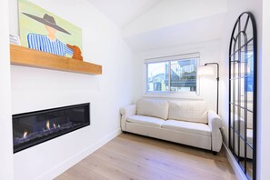 Una sala moderna con chimenea, un sofá, un ventanal con vistas y un cuadro en la pared.