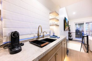 A modern kitchen with a built-in sink, a coffee machine, and a wooden countertop. - 1111 Woodside Ave (Park City)