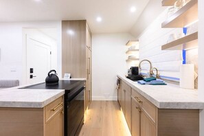 A modern kitchen with wooden cabinets, a black kettle, and a countertop with a sink and dish soap. - 1111 Woodside Ave (Park City)