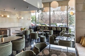 A restaurant with indoor seating, tables, chairs, and pendant lighting. - NJV Athens Plaza (Athens)