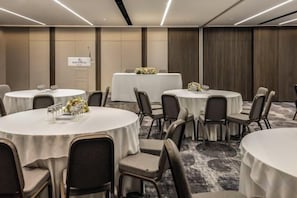 A conference room with round tables, chairs, and a stage with a podium. - NJV Athens Plaza (Athens)
