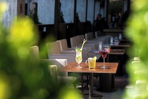 An outdoor dining area with tables and chairs, some with drinks. - NJV Athens Plaza (Athens)