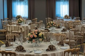 A banquet hall with round tables set for a formal event, featuring floral centerpieces and neatly arranged table settings. - NJV Athens Plaza (Athens)