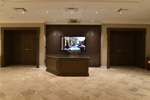 A lobby with a large television, a reception desk, and a tiled floor. - NJV Athens Plaza (Athens)
