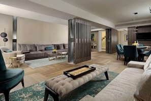 A modern living room with a sofa, coffee table, and ottoman. There is a dining area with chairs and a table. - NJV Athens Plaza (Athens)