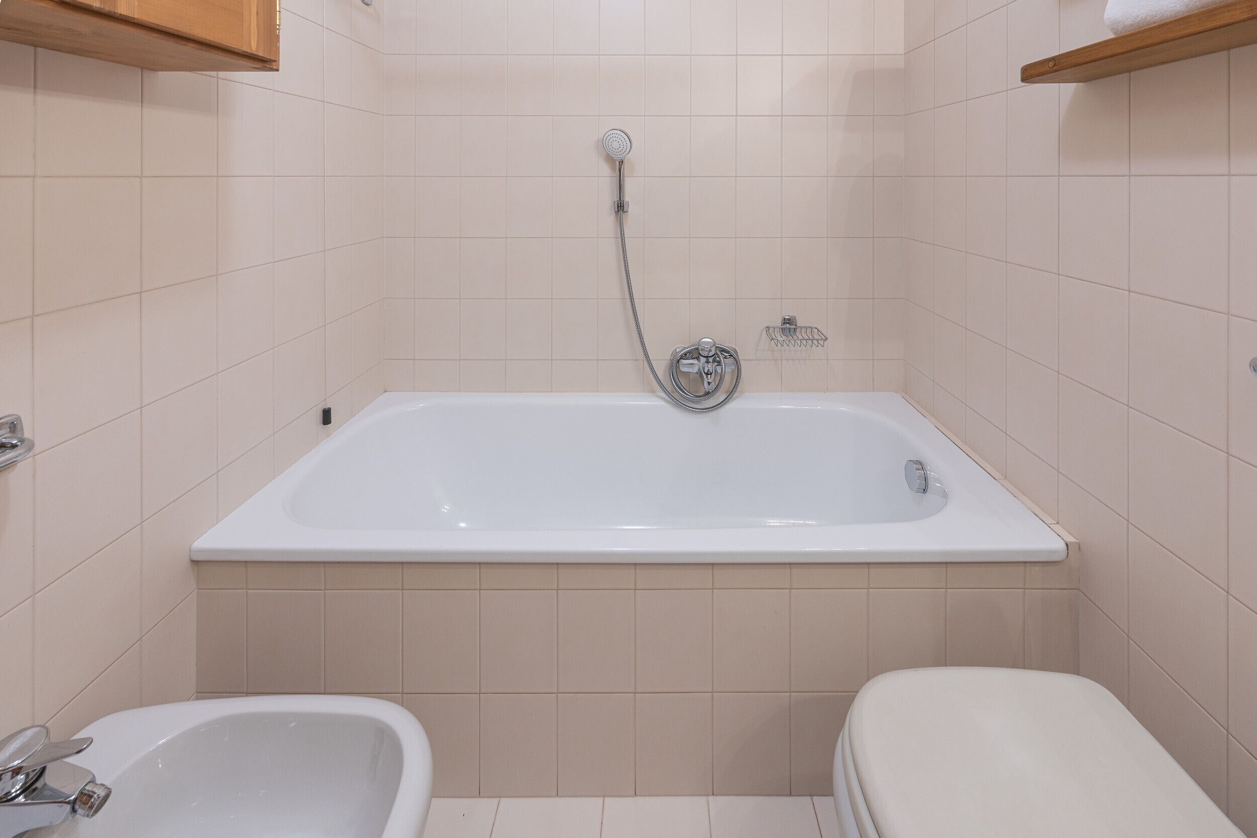 A bathroom with a bathtub, two sinks, and a showerhead.