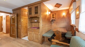 Interior acolhedor de uma cabana com paredes de madeira, uma mesa de jantar, bancos e armários embutidos.