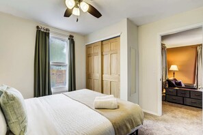 A bedroom with a bed, a ceiling fan, a wardrobe, and a bathroom visible through an open door.