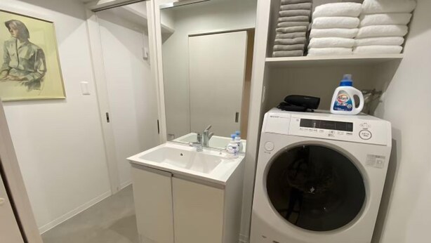 A compact bathroom with a sink, mirror, and a washing machine. - Core Royal-Vacation Rental (Kyoto)