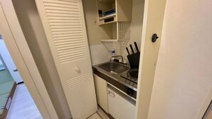A compact kitchen with a sink, stove, and cabinets. - Core Royal-Vacation Rental (Kyoto)