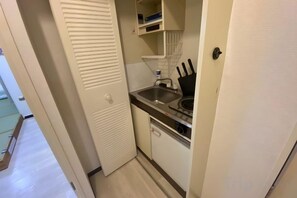 A compact kitchen with a sink, stove, and cabinets. - Core Royal-Vacation Rental (Kyoto)