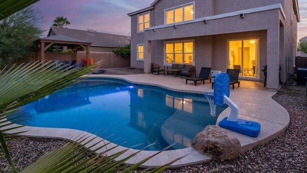 A modern two-story house with a swimming pool, outdoor seating, and a covered patio. - Desert Retreat | Pool | Fire Pit | Family Games (Surprise)