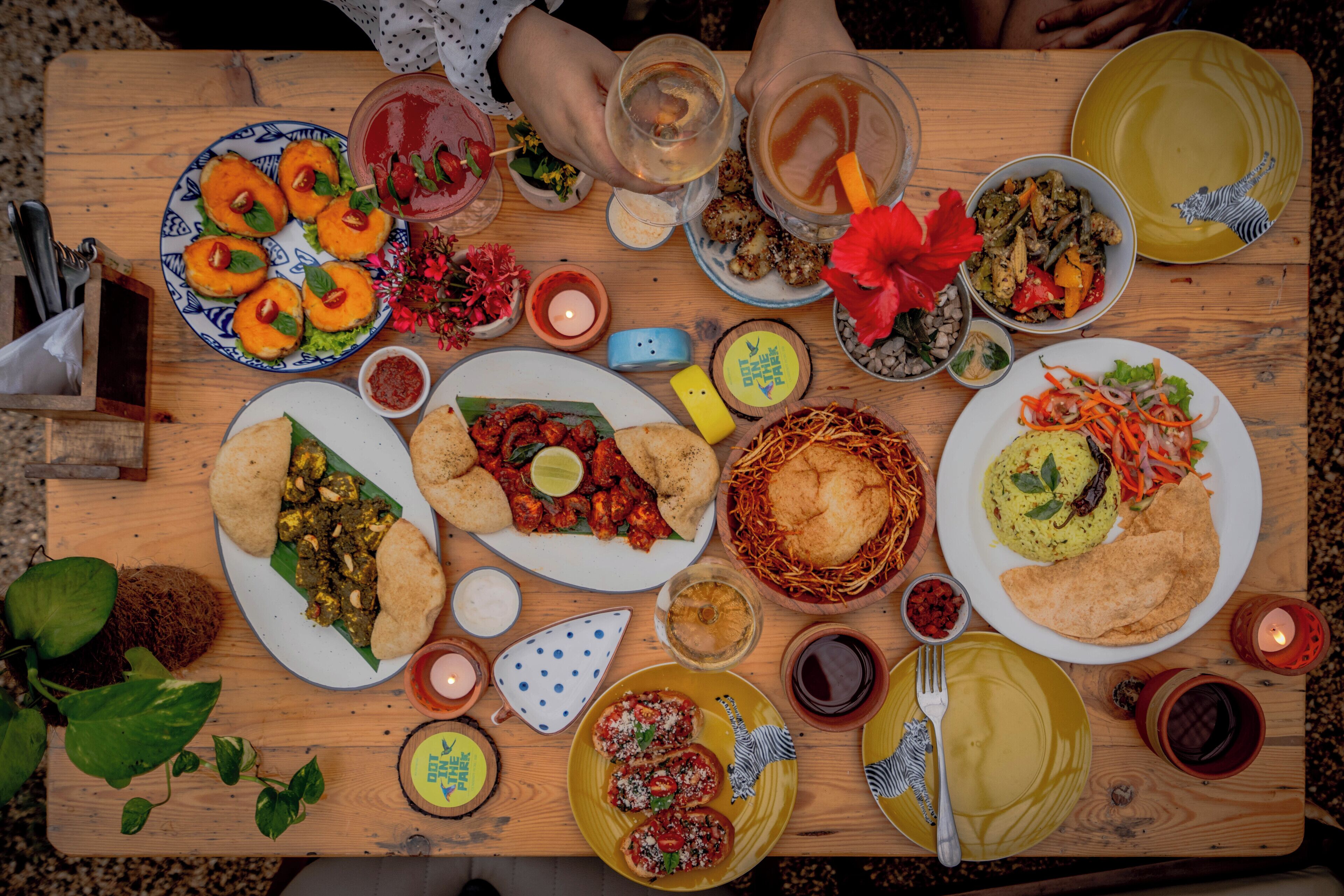 Una mesa de madera con varios platos, bebidas y una vela.