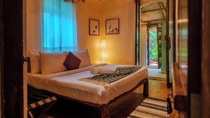 A bedroom with a bed, pillows, a bedside lamp, and framed pictures on the wall. - Circle Goa (Anjuna)